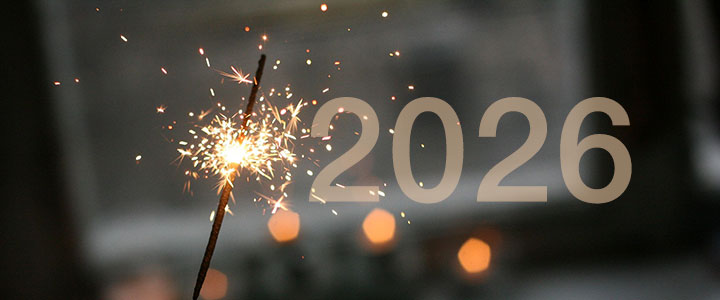 Eine brennende Wunderkerze vor einem dunklen Hintergrund, daneben die Zahl 2026